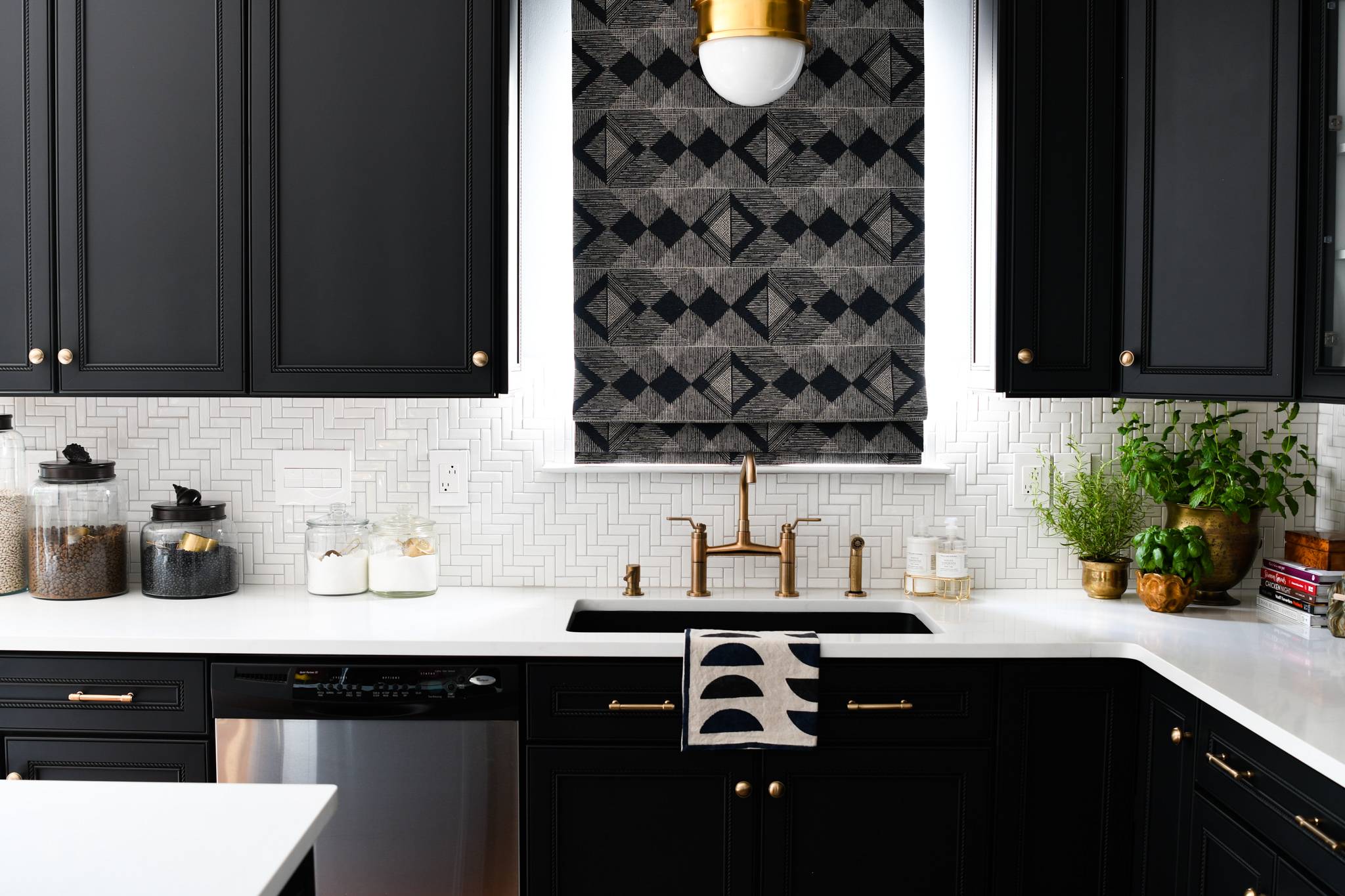 modern kitchen with black cabinets and white herringbone tiled backsplash