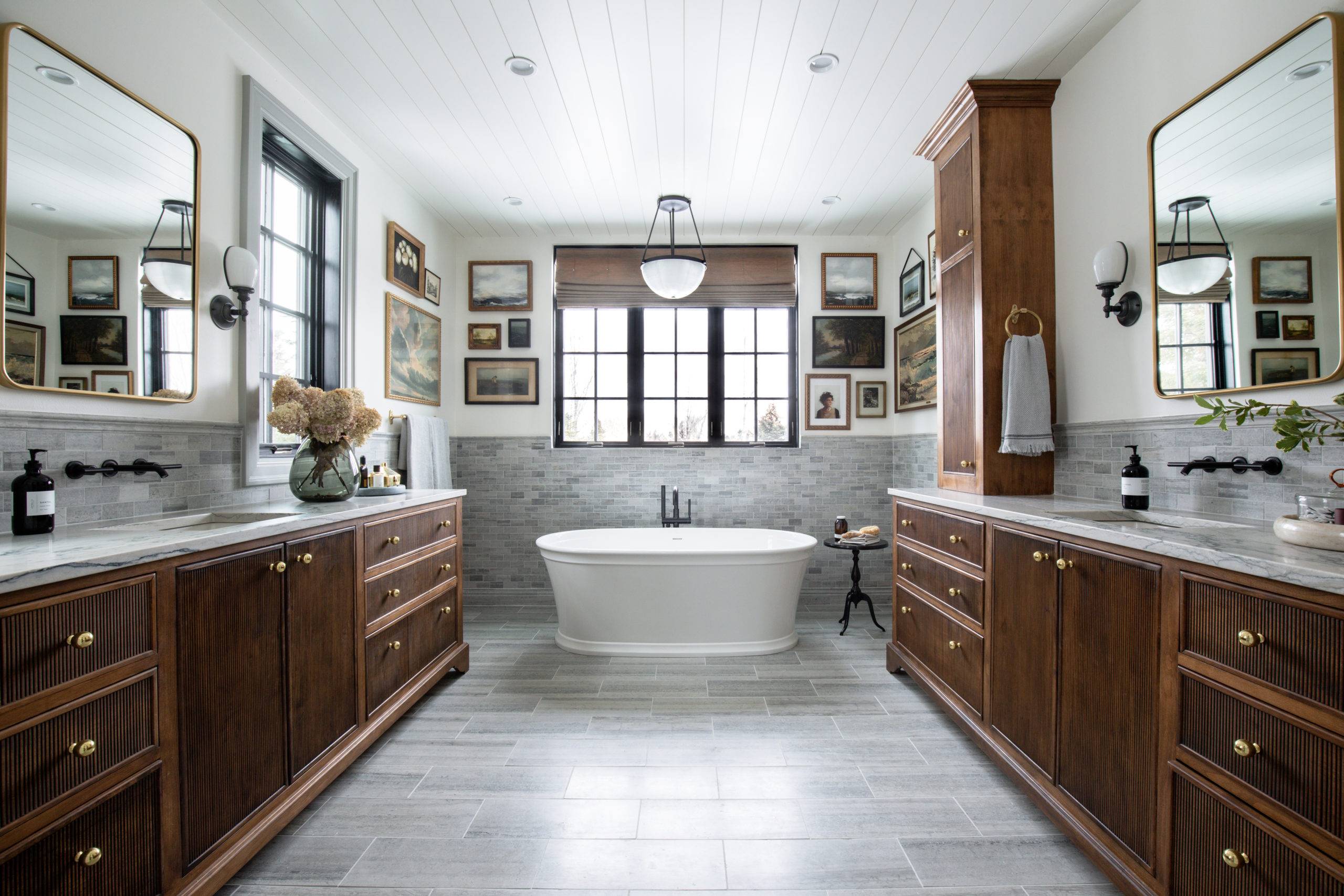 Large primary bathroom with grey limestone tile and dark brown wood vanities