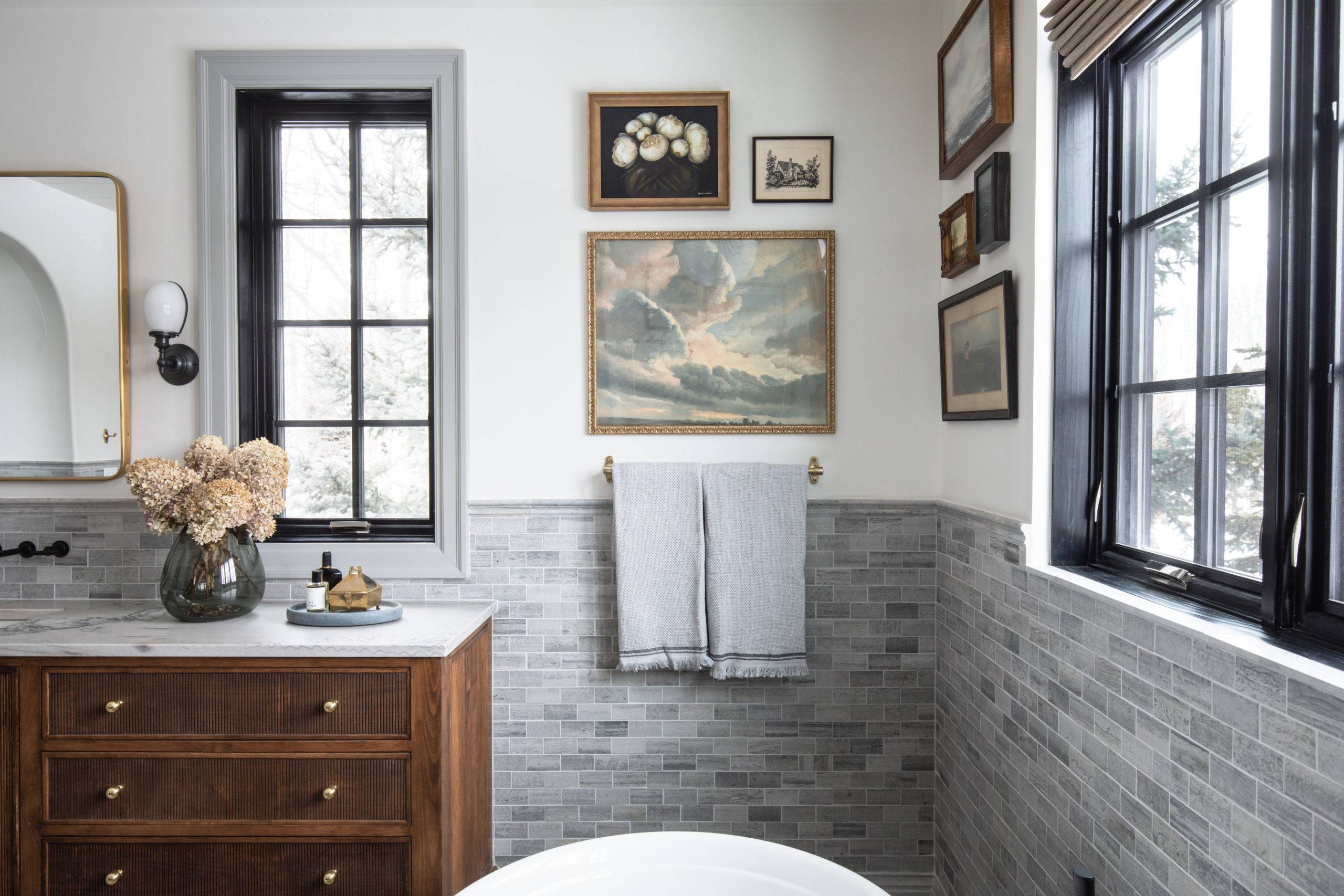White primary bathroom with grey limestone tiled backsplash and brown wooden vanity