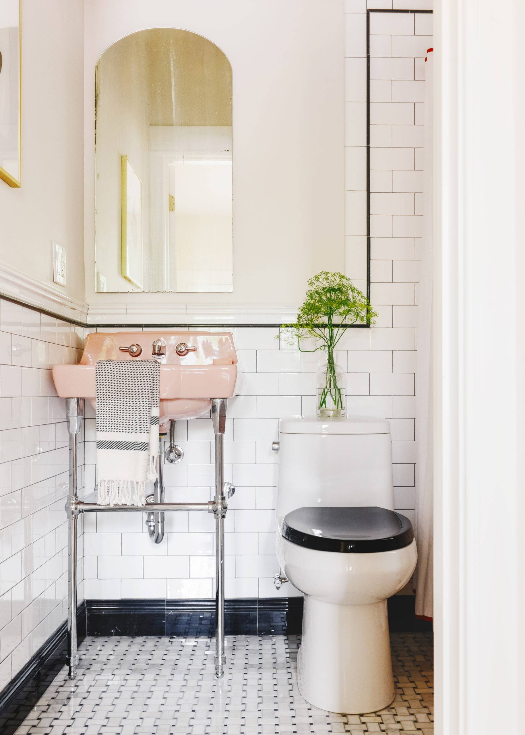 Small tiled bathroom with white subway tile backsplash and marble mosaic flooring with vintage pink sink