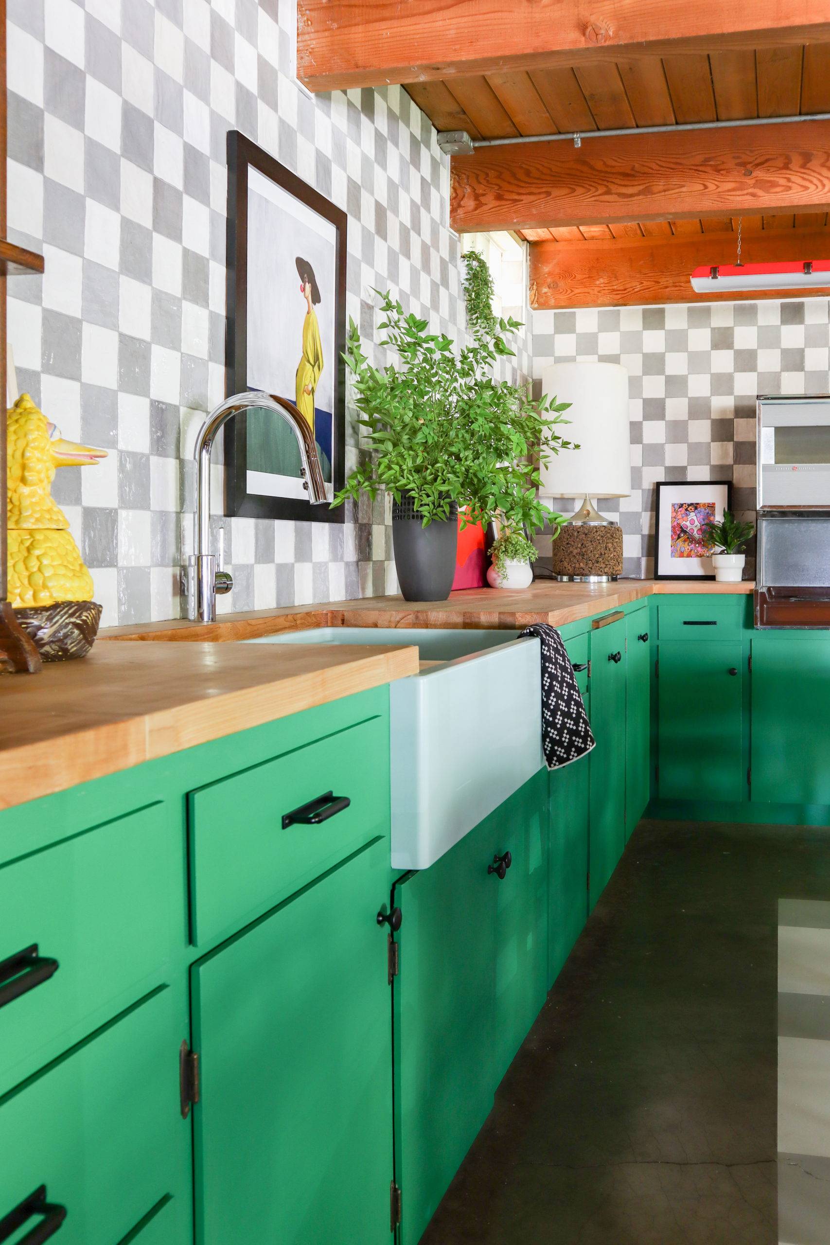 Eclectic basement kitchen with green cabinetry and tiled checkerboard backsplash