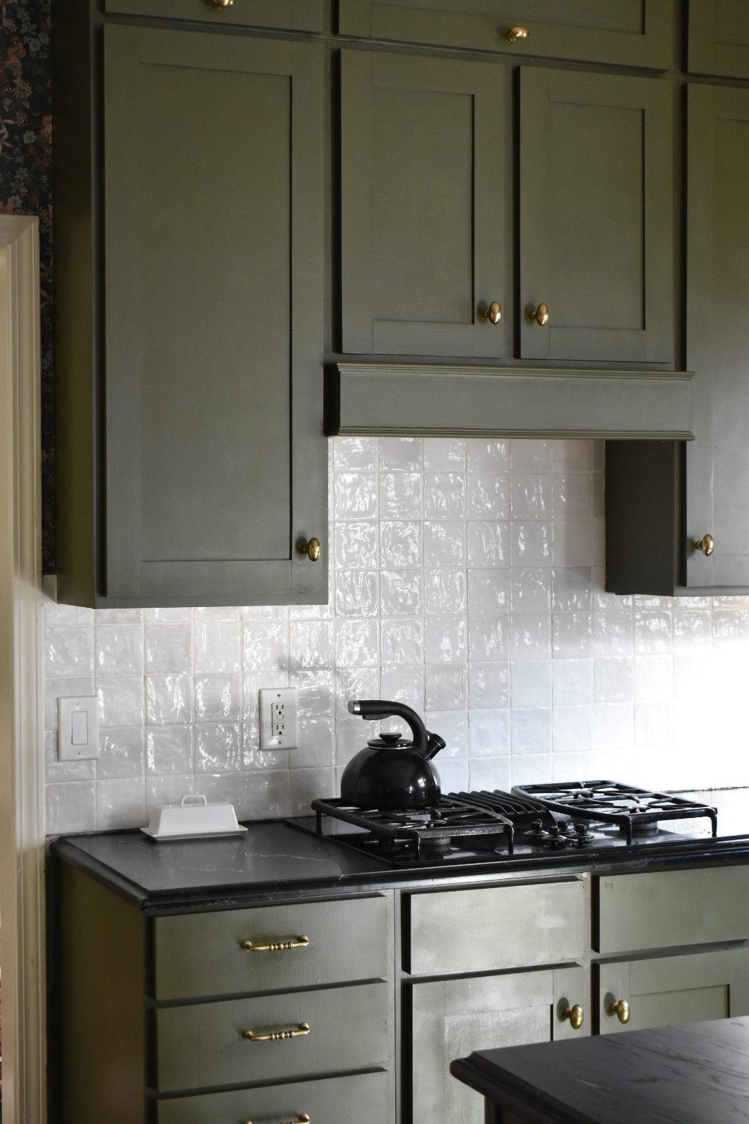 Moody kitchen with olive green cabinetry and white handmade-look tiled backsplash