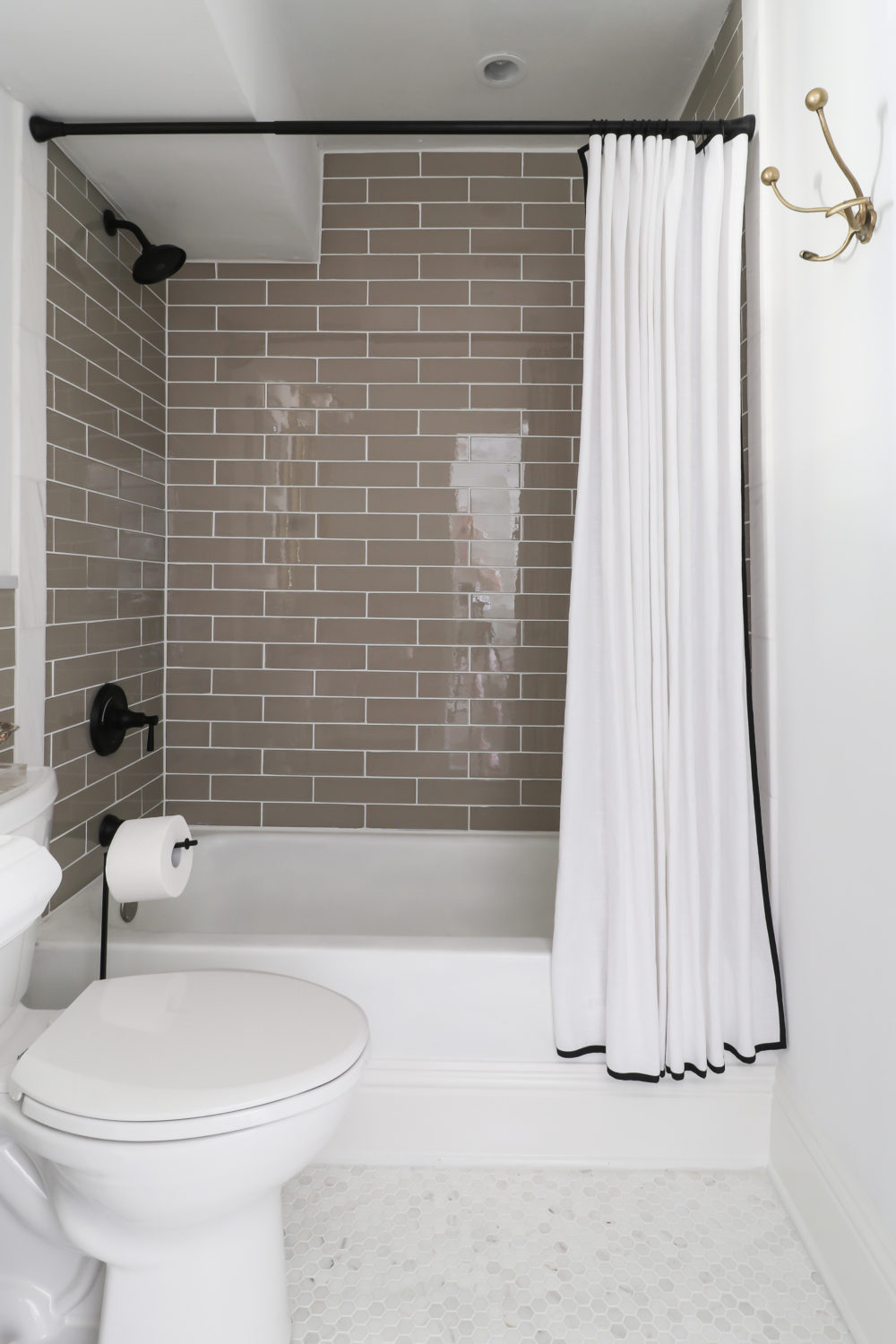 Bathroom featuring taupe subway tile shower and white marble hex flooring