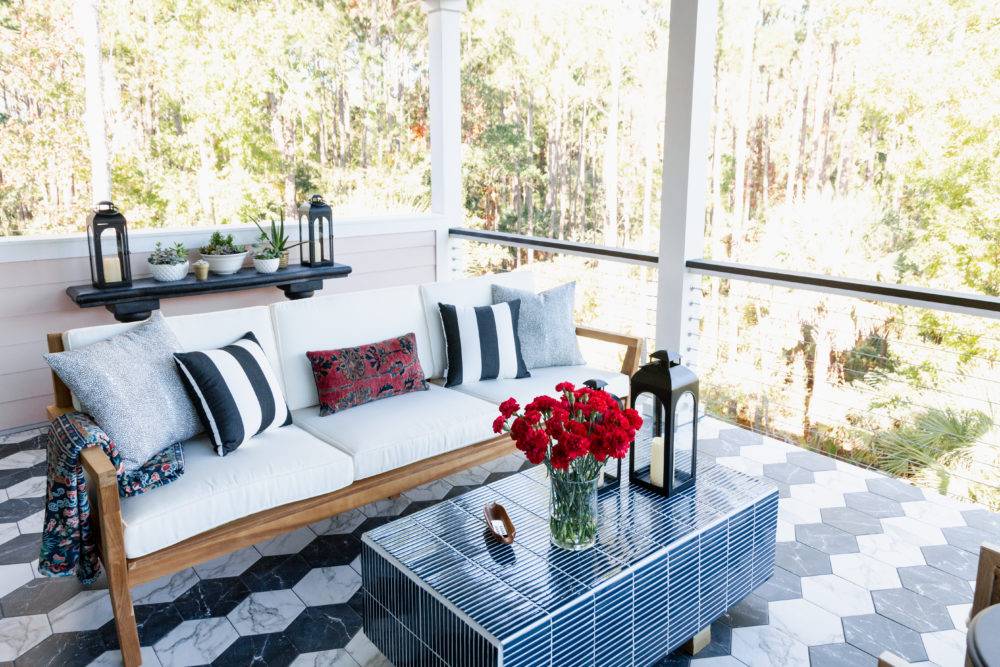 Porch with black and white tiled hexagon flooring and tiled outdoor coffee table next to patio furniture