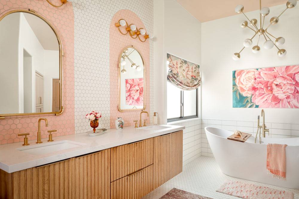 Art deco bathroom with fluted wood vanity and tiled backsplash with pink arches above sink