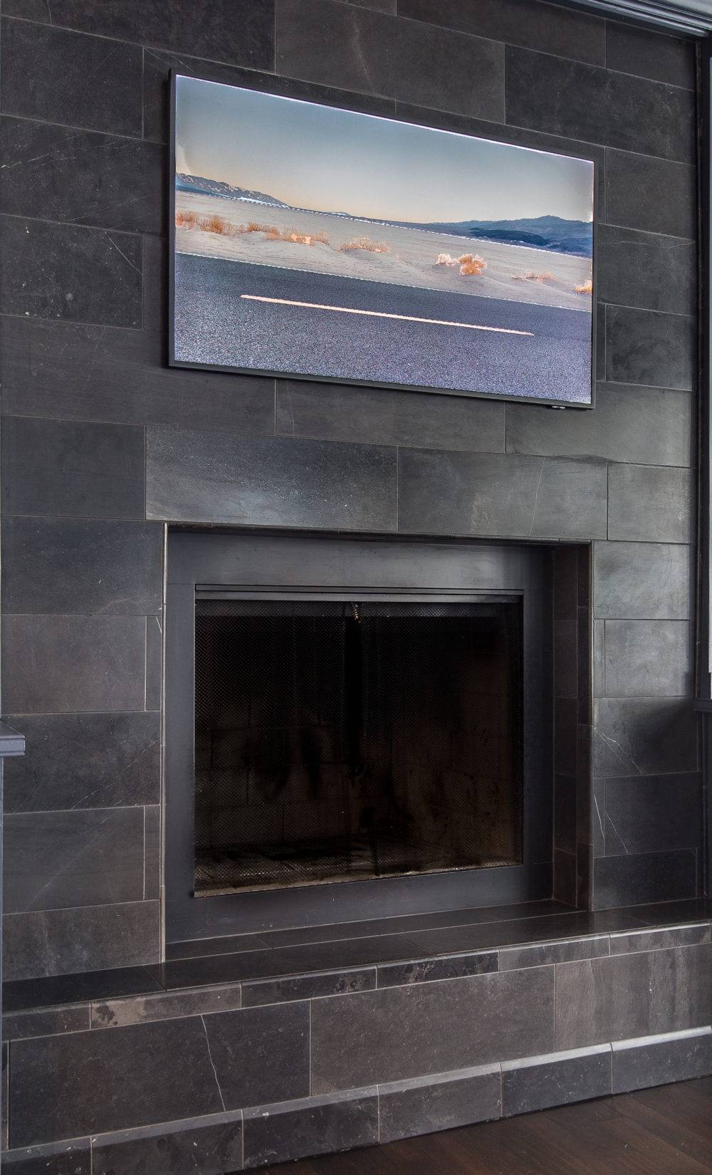 Black travertine tiled fireplace with mounted picture frame tv 