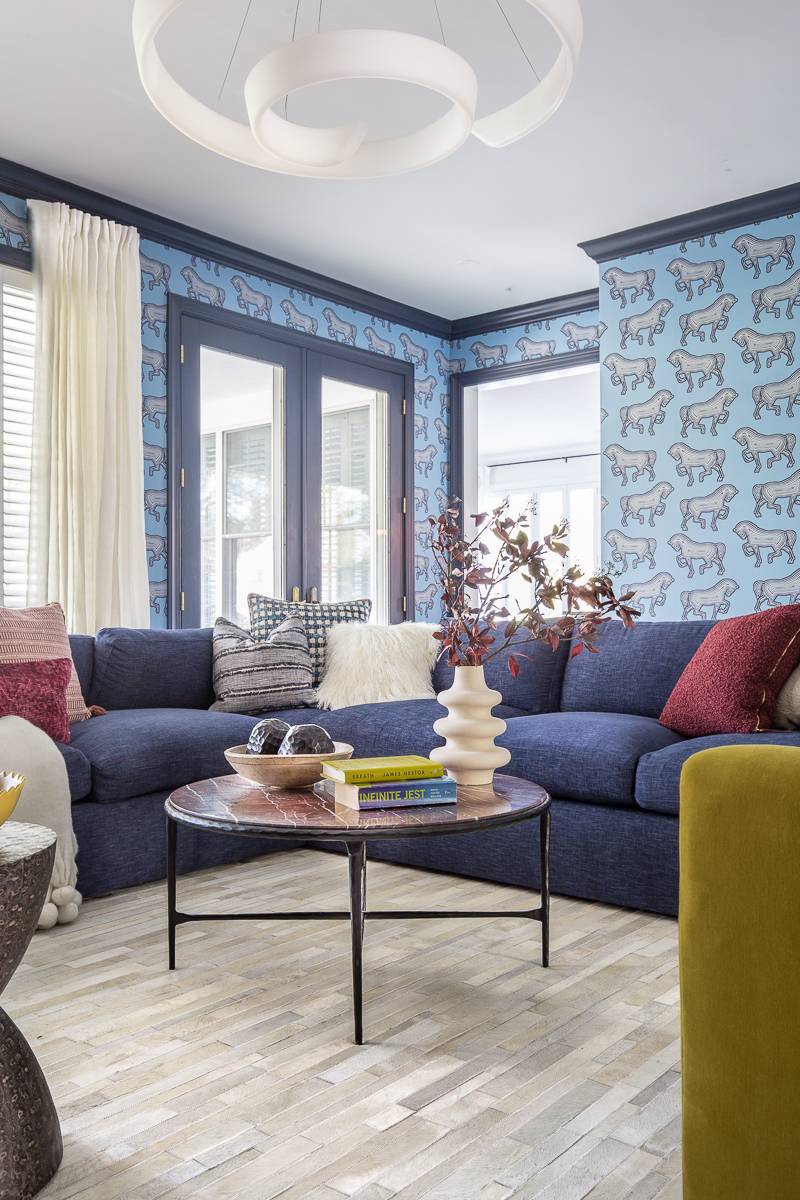 Colorful maximalist living room with large white spiral chandelier and blue patterned wallpaper