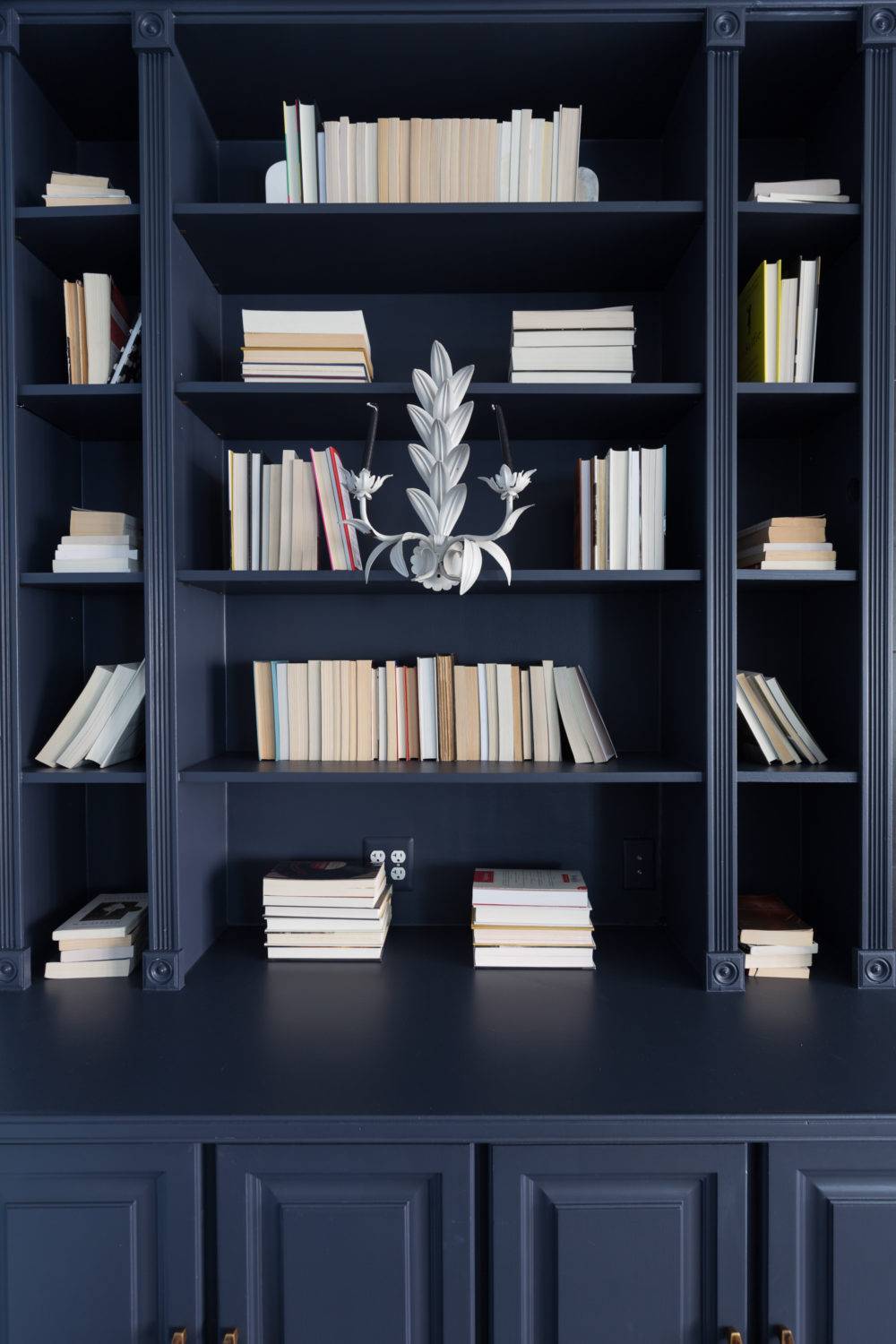 Dark blue bookshelf with stacked books