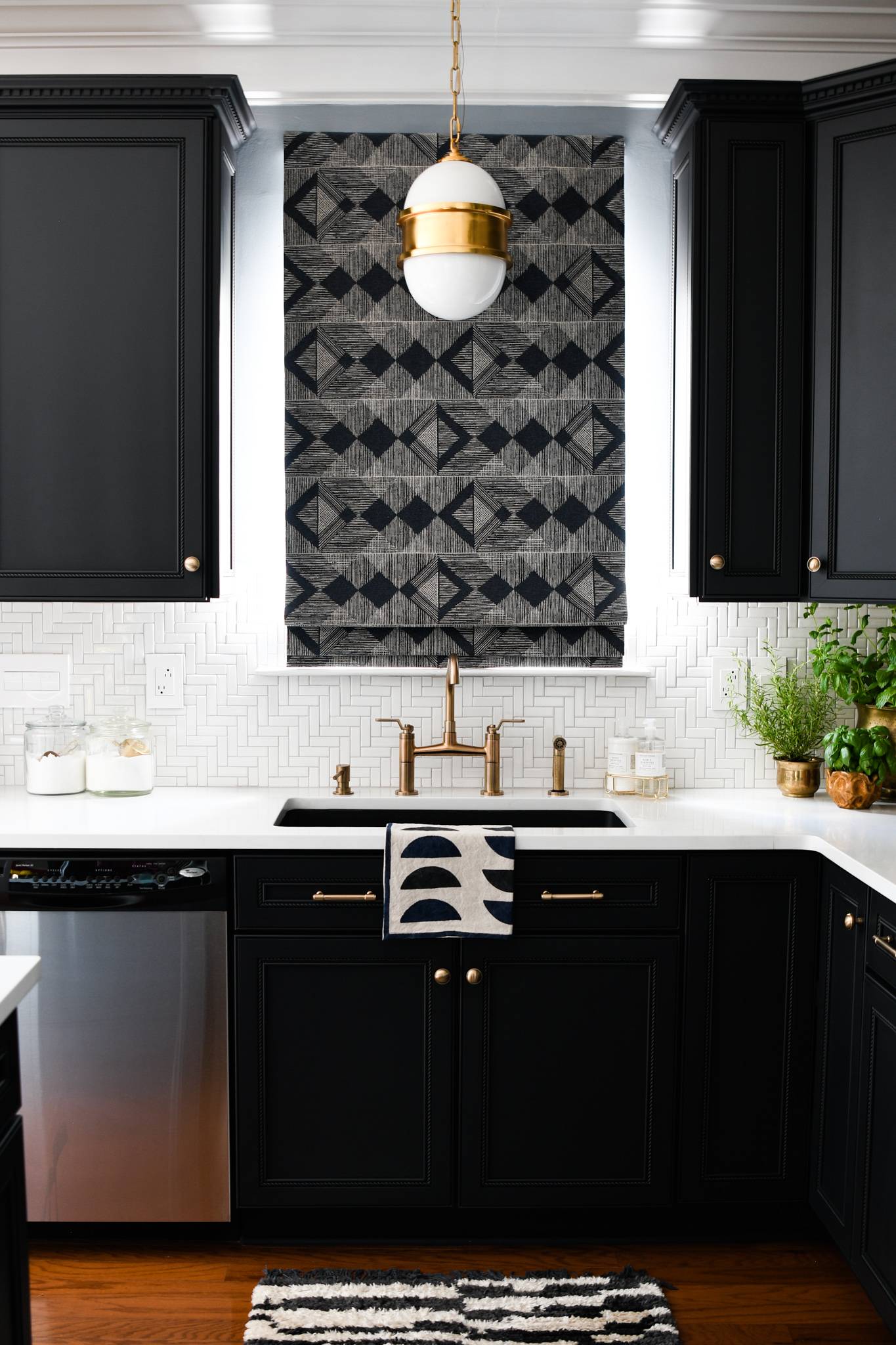 Glamorous kitchen with black cabinetry and white herringbone mosaic backsplash