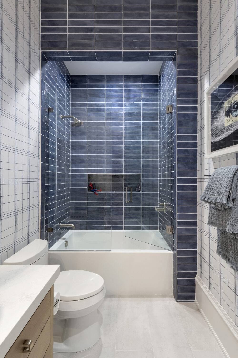 Boys' blue bathroom shower featuring Ionic White, Splendours Blue Night and Splendours Blue Night trim tile. 