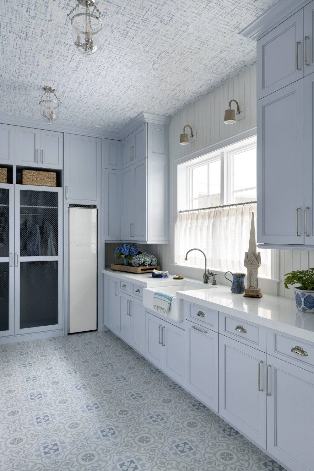 Laundry room with light-blue cabinets featuring Decora Ornament Blue and Annie Selke Crosshatch Sky tile. 