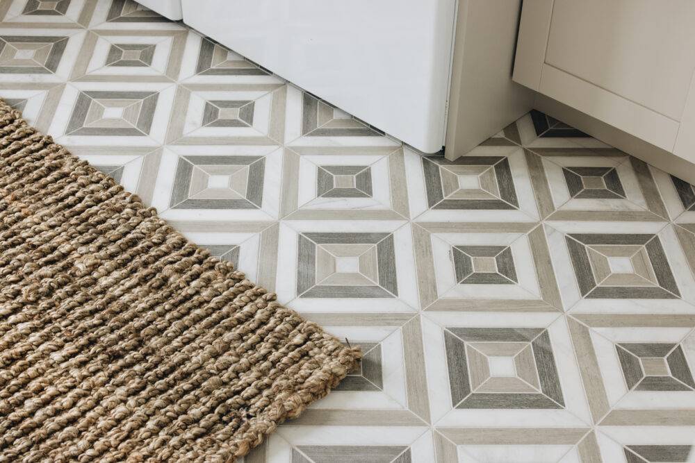 Beige and grey laundry room with grey square-patterned tile floor. 
