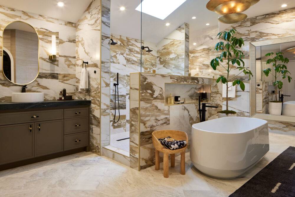 Large bathroom with white marble floors and white with dramatic ochre and gold veining large-format marble-look porcelain tile walls. 