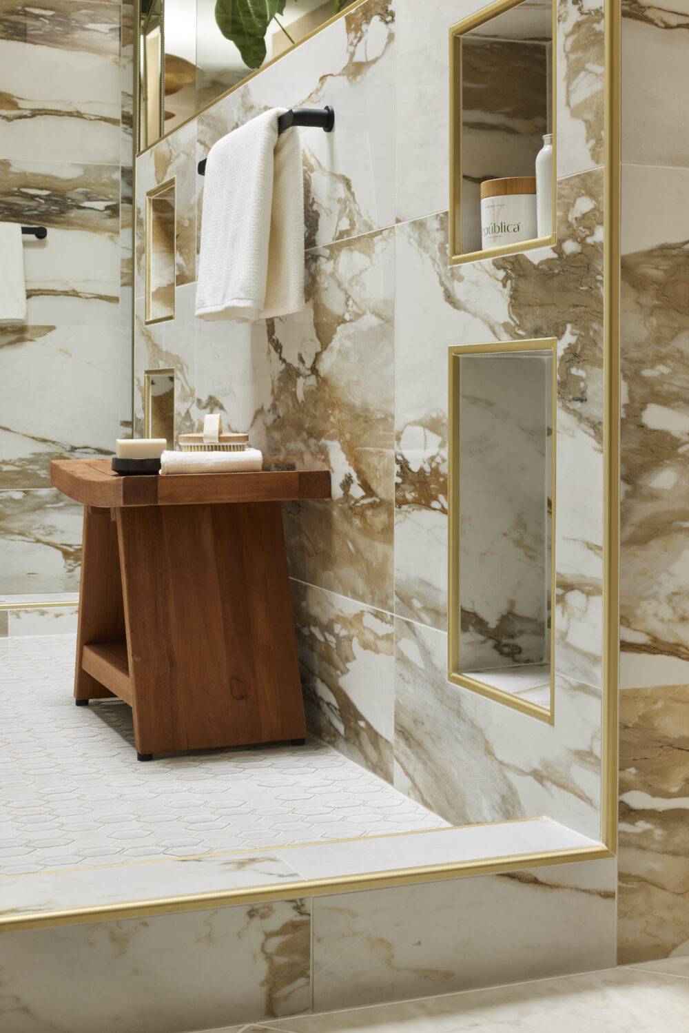Shower with white with dramatic ochre and gold veining large-format porcelain tile walls and white elongated hex porcelain floor. 