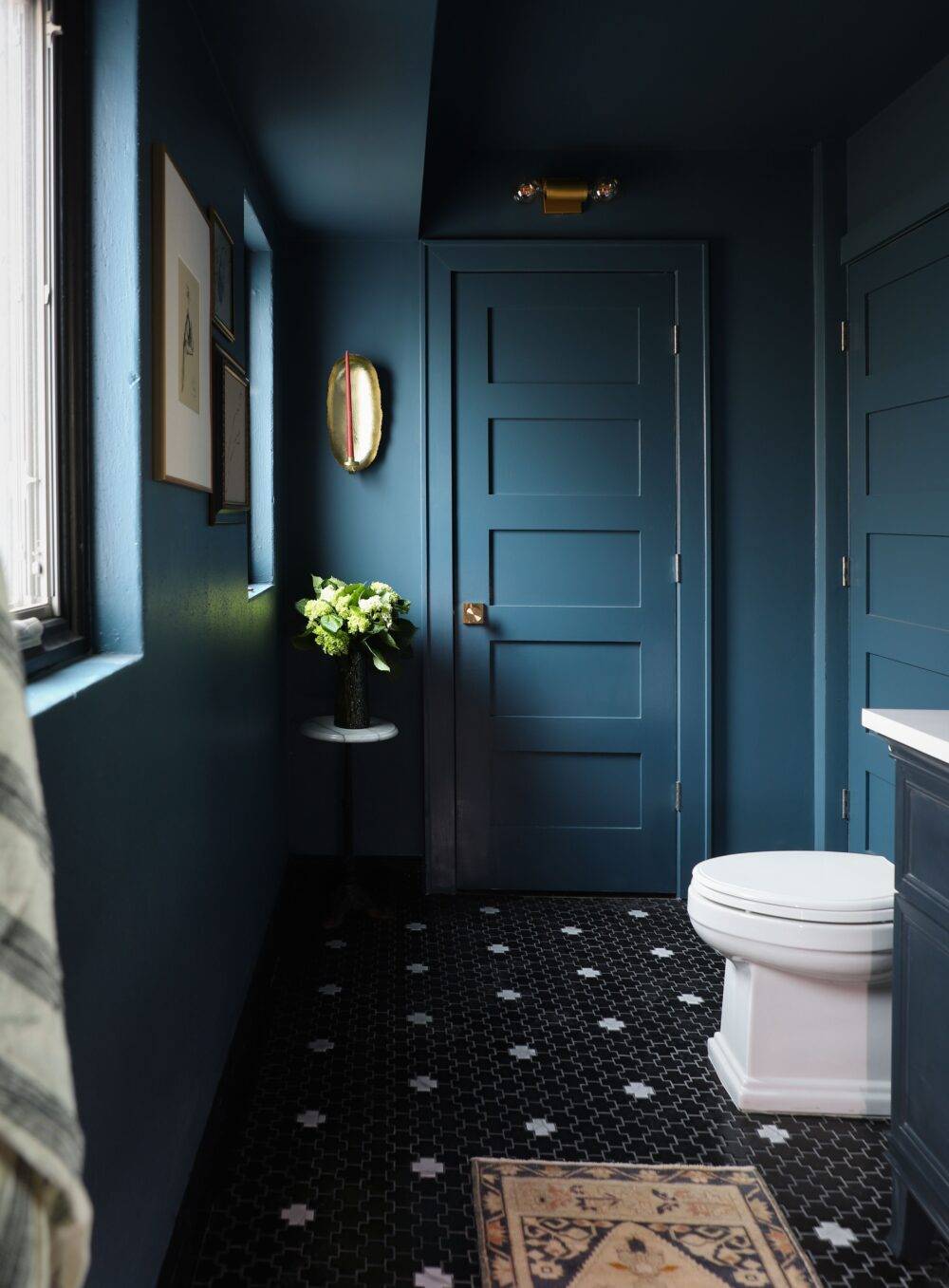 Blue bathroom with black and white cross tile floor. 