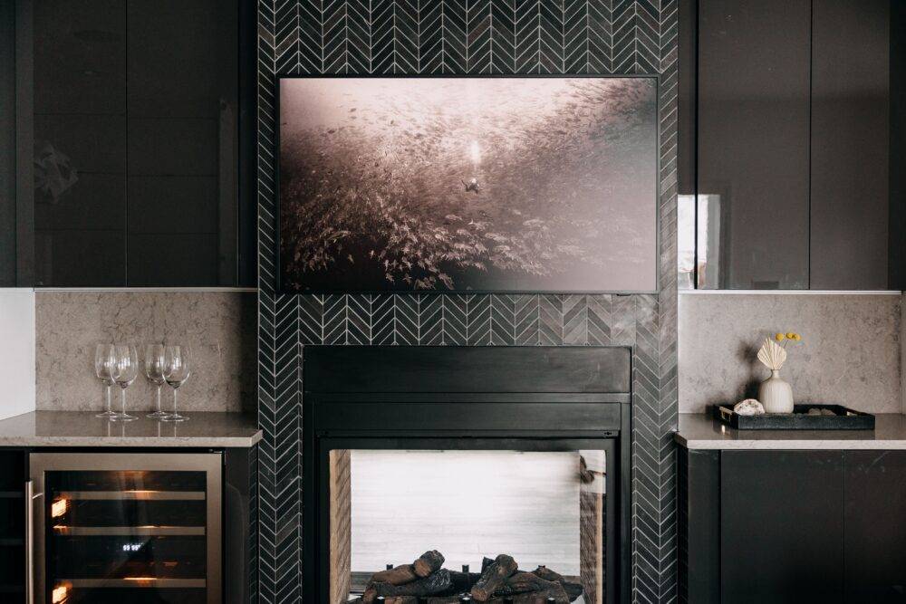 TV mounted above a fireplace with black chevron tile. 
