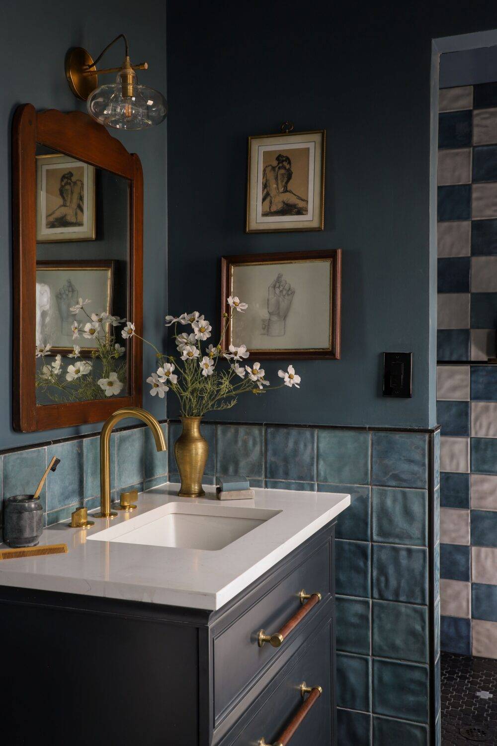 Bathroom with blue and white square handmade-look tiles. With framed drawings and flowers. 
