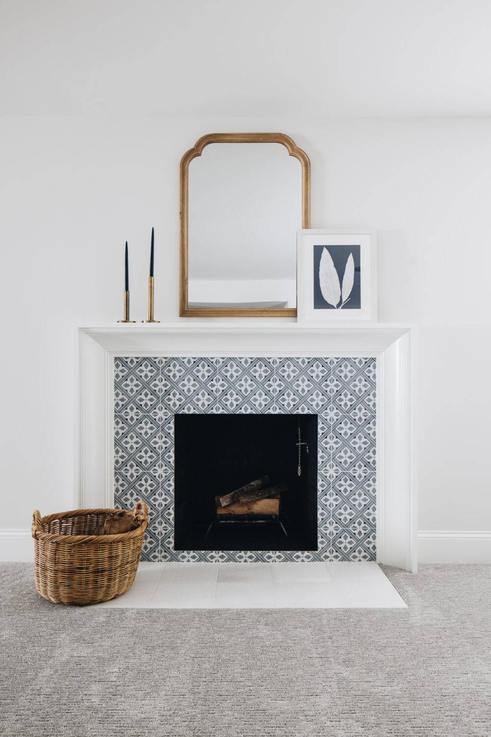 Blue and white patterned fireplace surround with gold and blue accessories on the white mantle. 