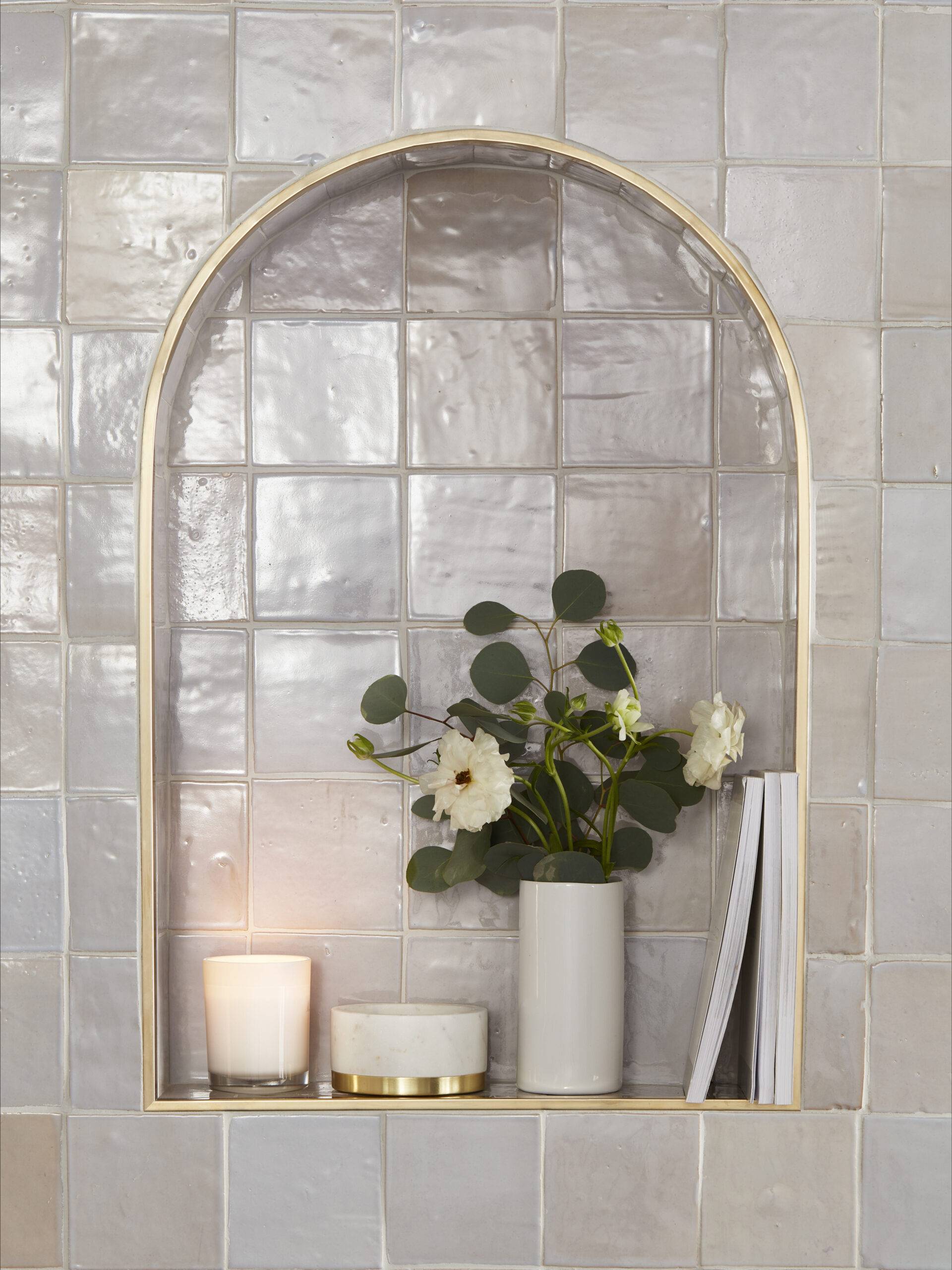 Cream-colored handmade tile recessed shelf with a candle and flowers. 