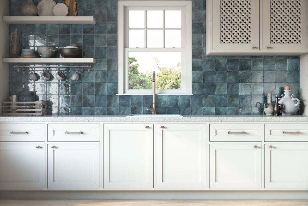Kitchen counter with white cabinets and square blue handmade-look tile. 