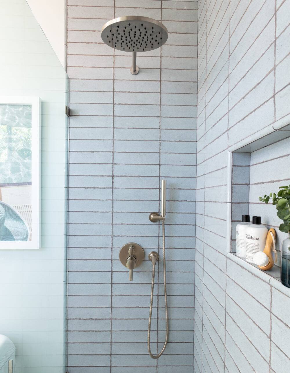 Small shower with blue handmade-look subway tile. 