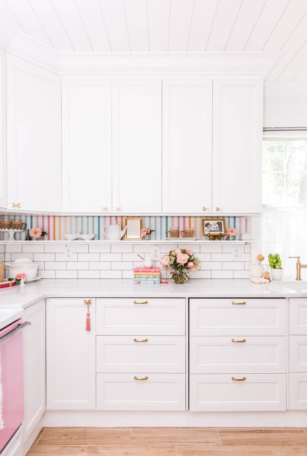 Kitchen with white cabinets and white subway tile and colorful accents. 