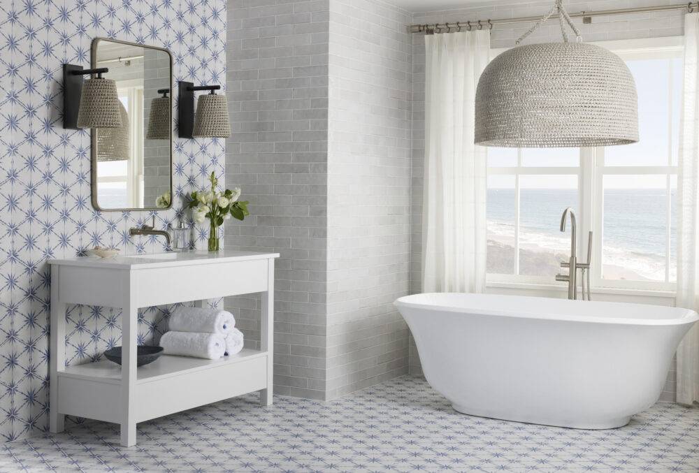 Coastal bathroom with blue and white patterned hexagon floor and wall and free-standing soaking tub.