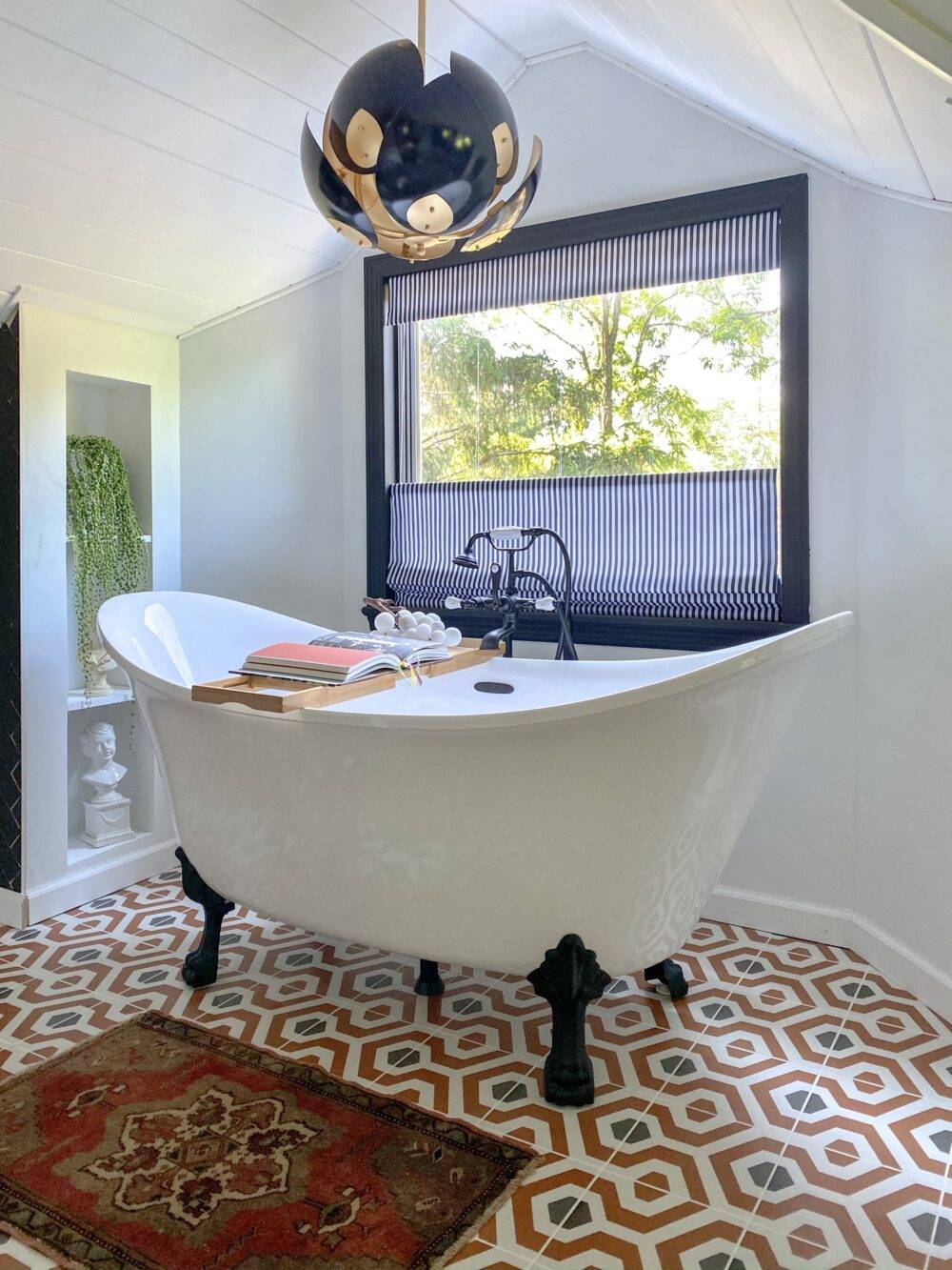 Free-standing soaking tub with geometric orange and black patterned floor tile. 