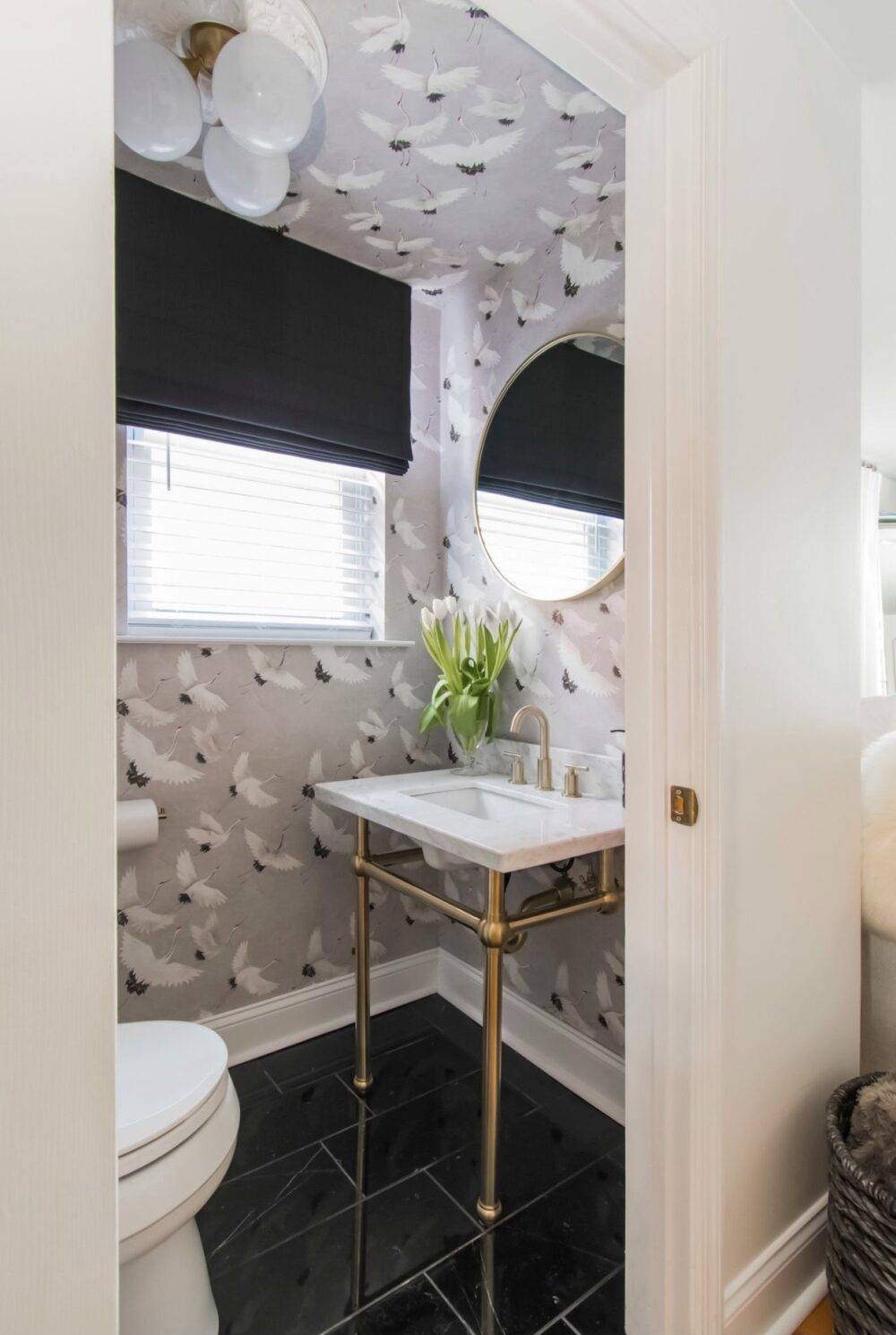 Powder room with bird-print wallpaper and black marble floor. 