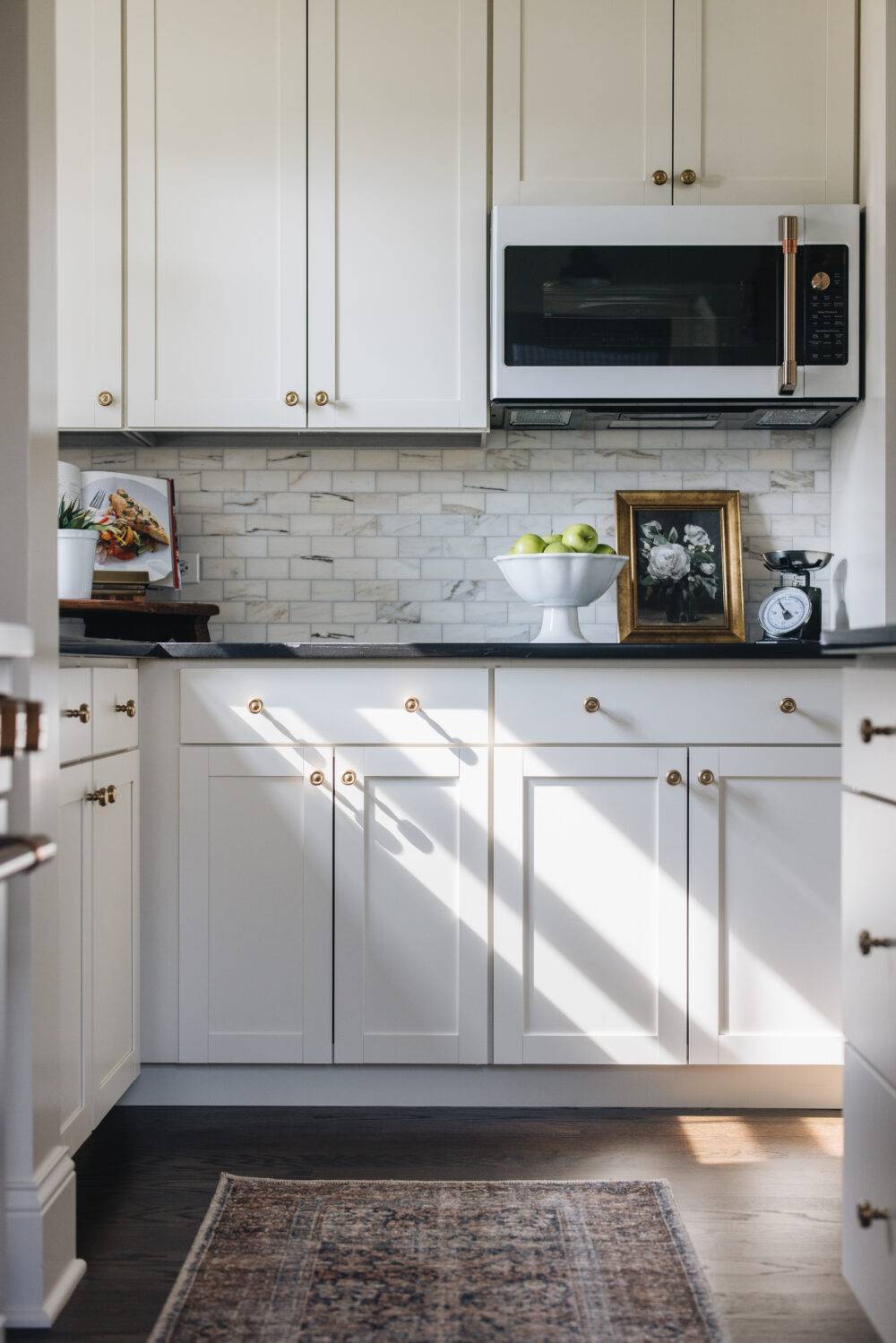 A kitchen with white cabinets and a small white marble subway tile backsplash. 