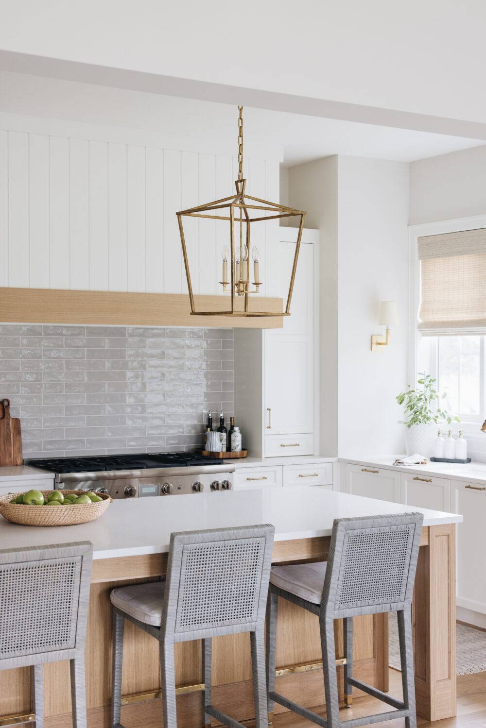 A kitchen with white cabinets and grey subway tile backsplash behind the stove. 
