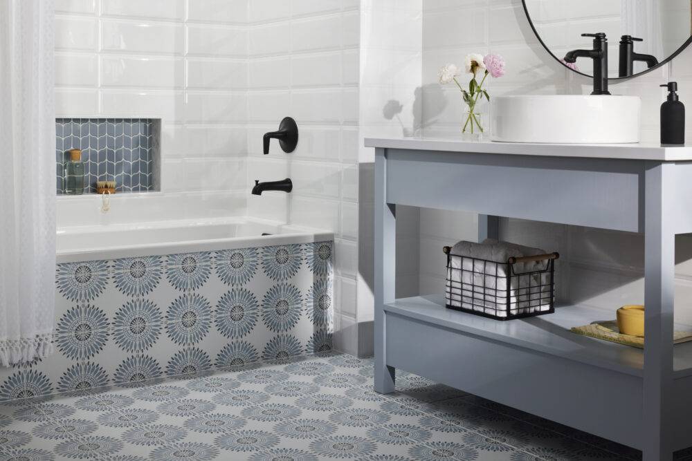 Blue and white bathroom with geometric floral floor tile and blue mosaic shower niche. 