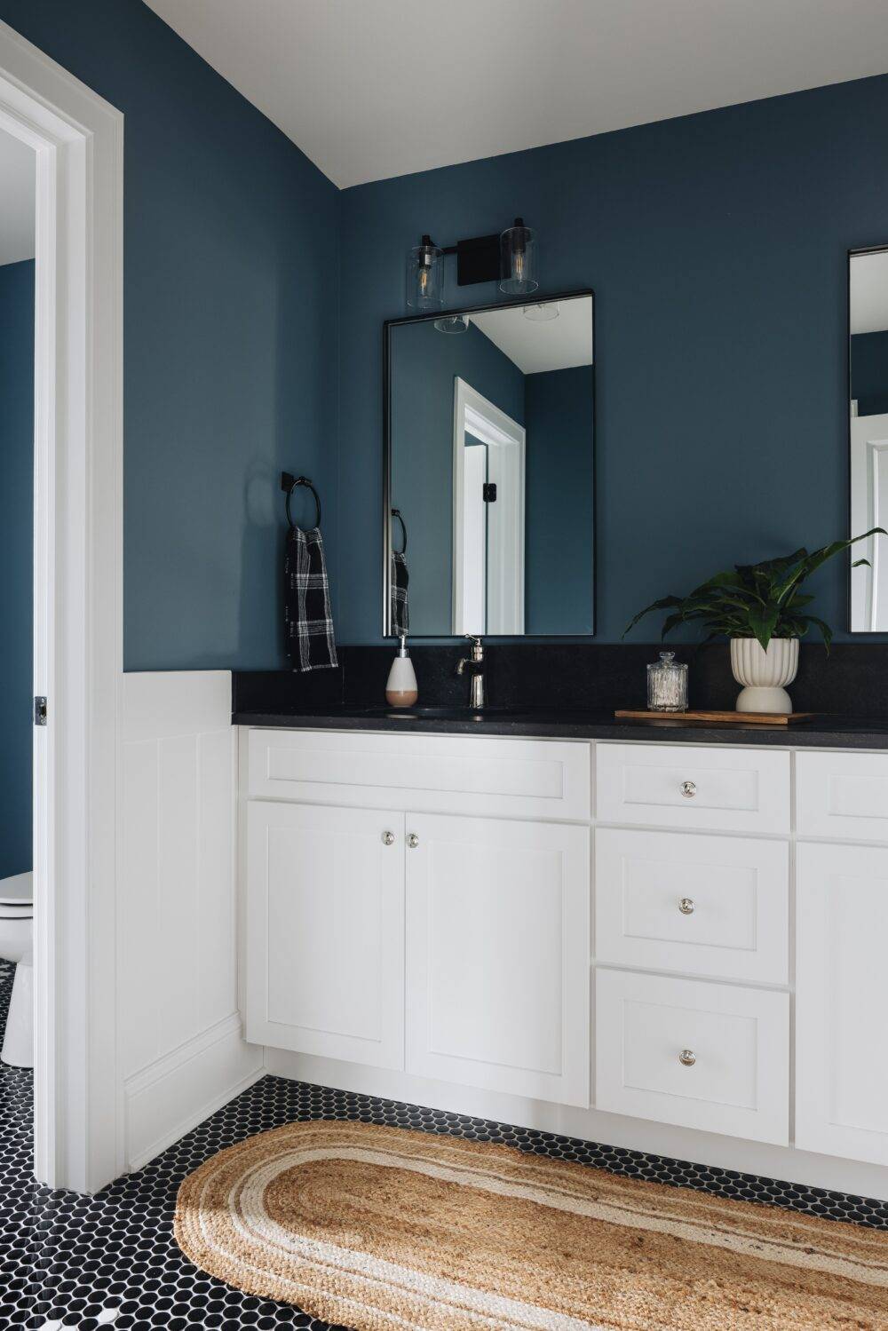 Blue bathroom with black and white quarter-round tile floor.