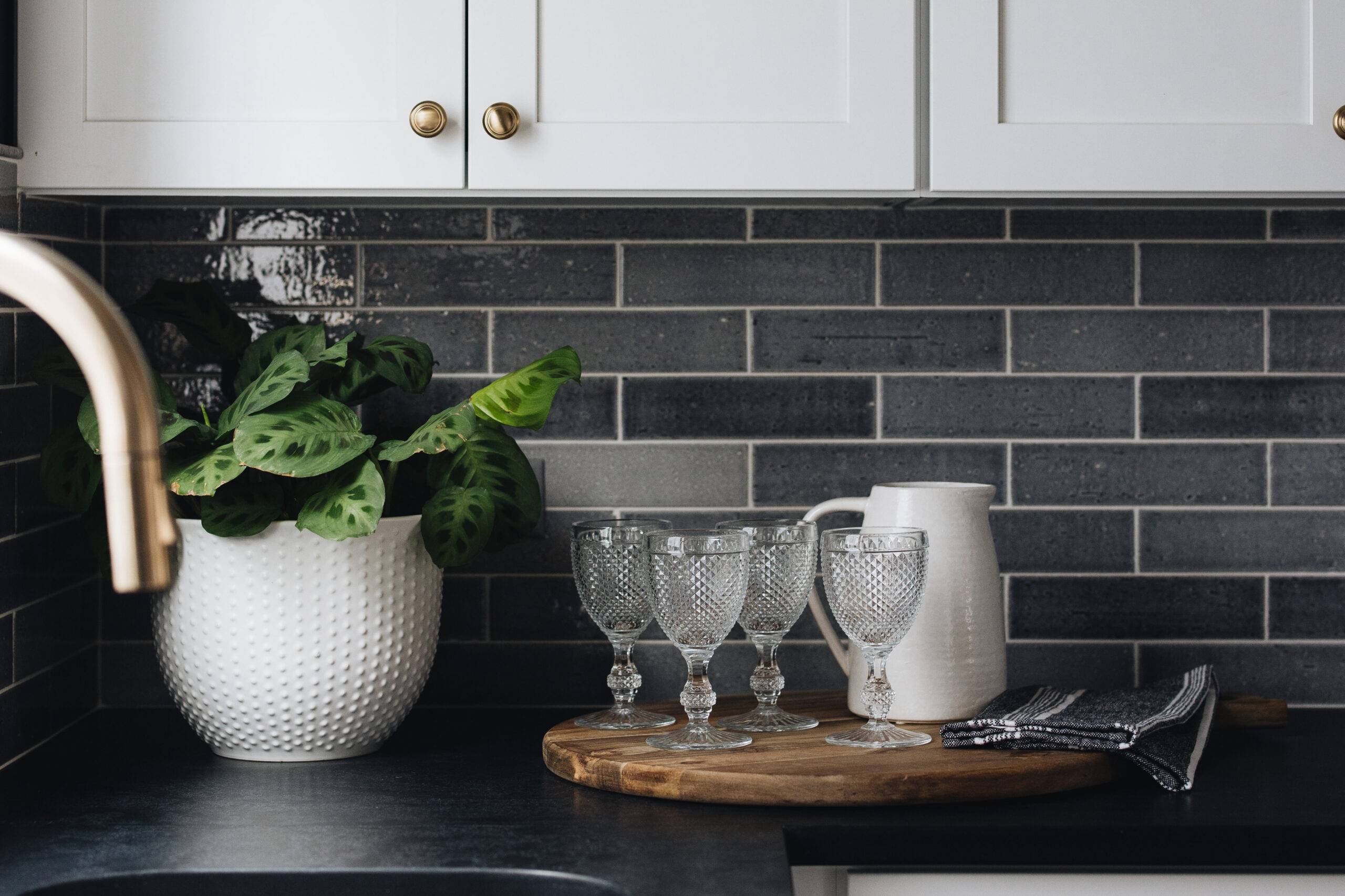 Grey brick-look tile backsplash with white kitchen cabinets. 