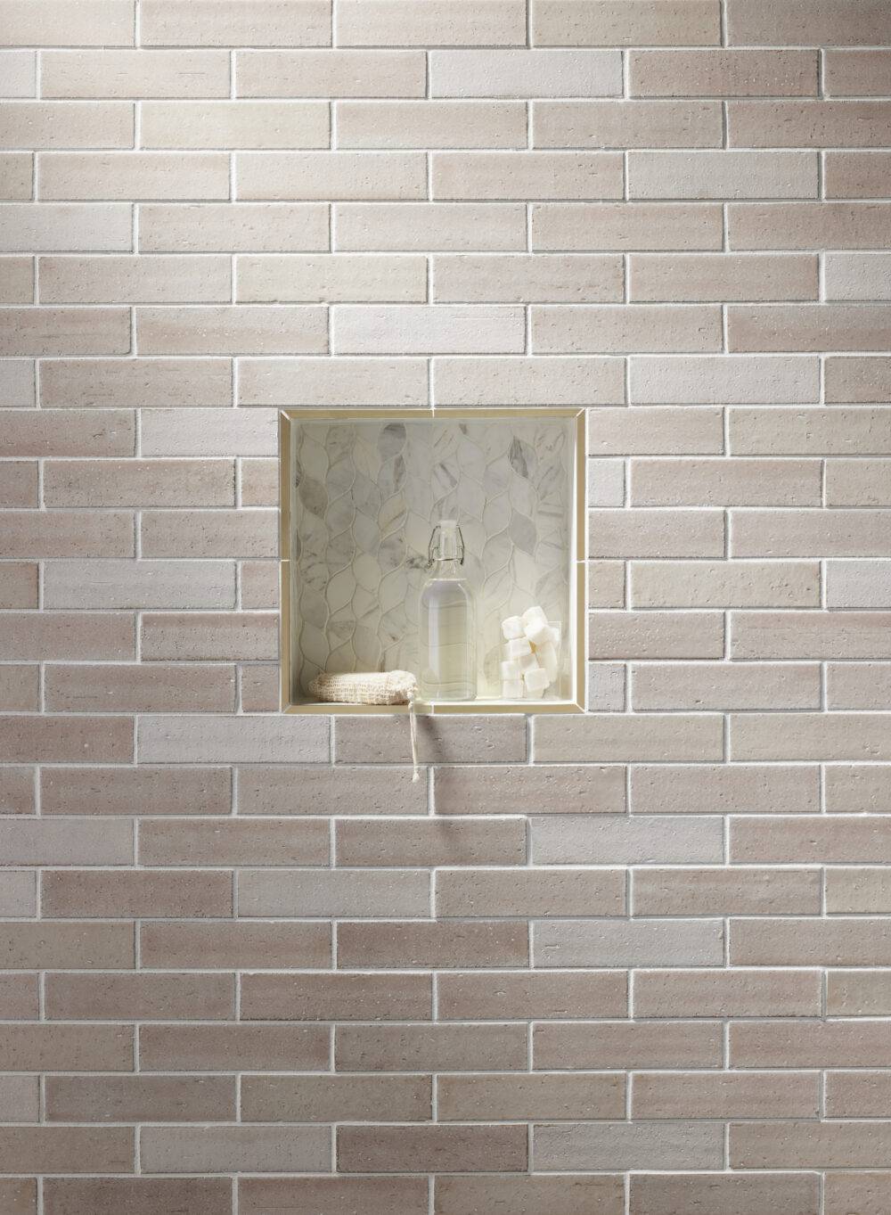Blush-colored brick-look subway tile with marble leaf-shaped shower niche. 