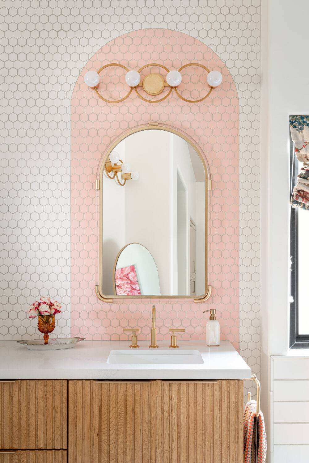 Bathroom with a white and pink tiled backsplash.