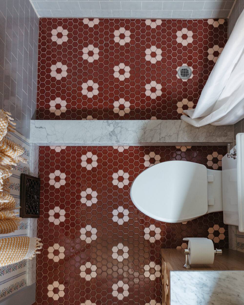 Overhead shot of a bathroom and shower with sienna-colored hexagon tiles with a pink hexagon floral pattern. 