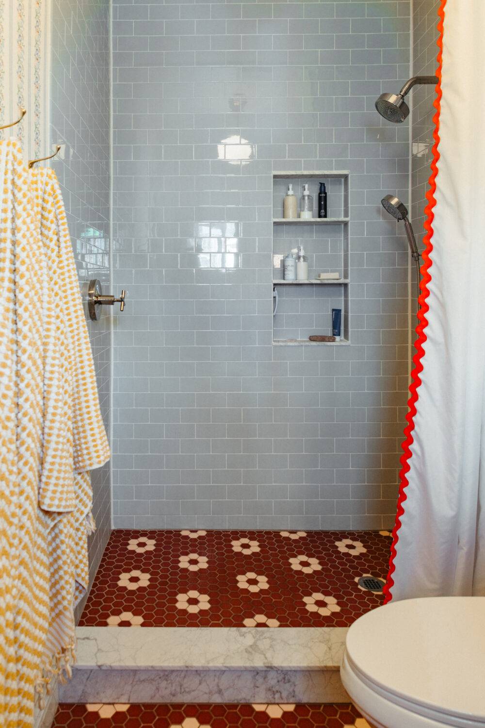 Overhead shot of a bathroom and shower with sienna-colored hexagon tiles with a pink hexagon floral pattern. 