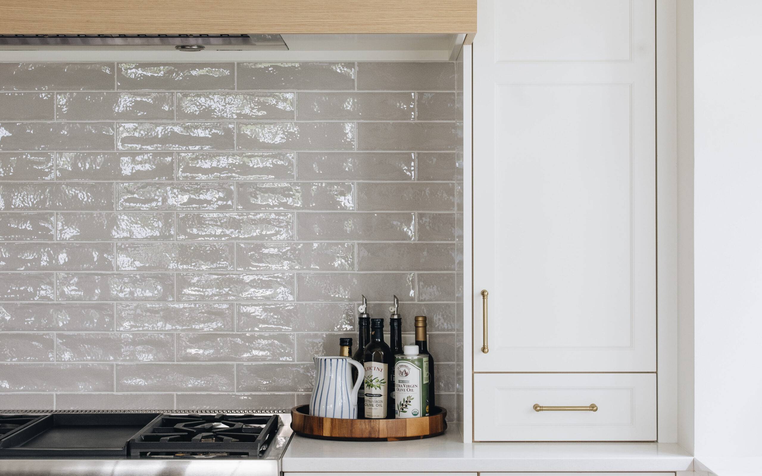 White tile kitchen backsplash with oven and white cabinets.