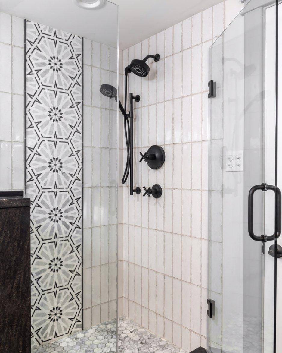 Shower with white subway tile and black and white floral mosaic vertical accent. 