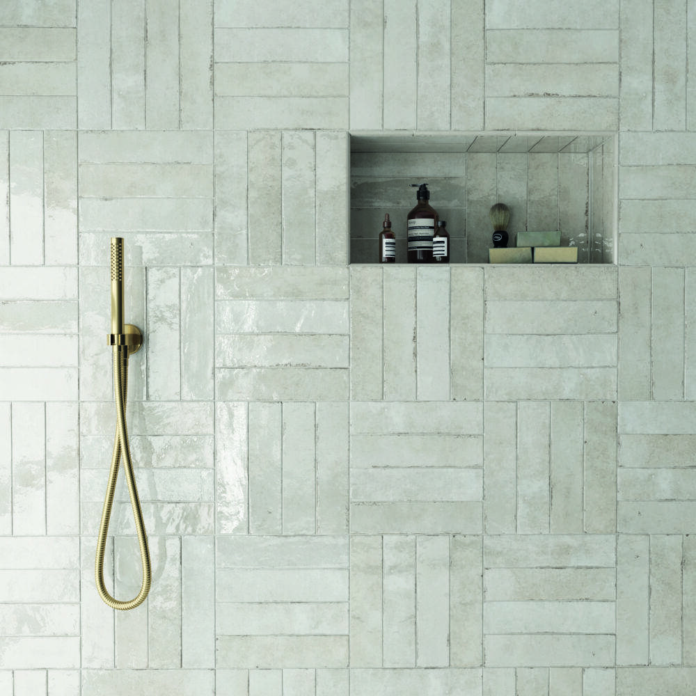A shower wall with an alternating pattern of horizontal and vertical stacked subway tile.