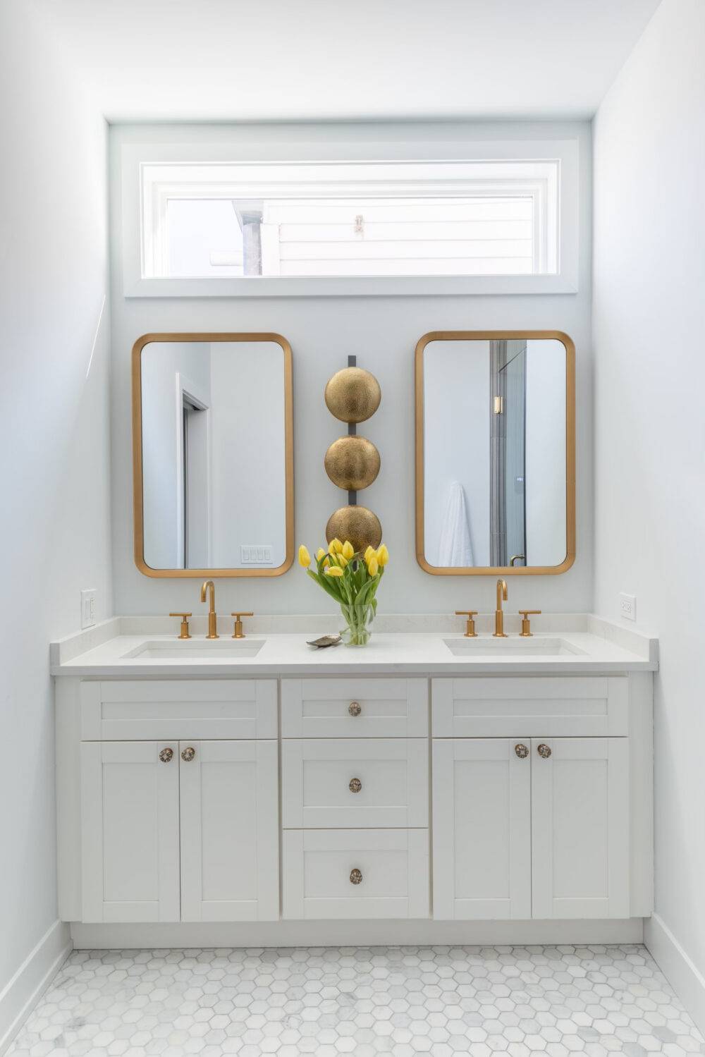 This bright modern white bathroom features a small hexagon marble tile floor. 