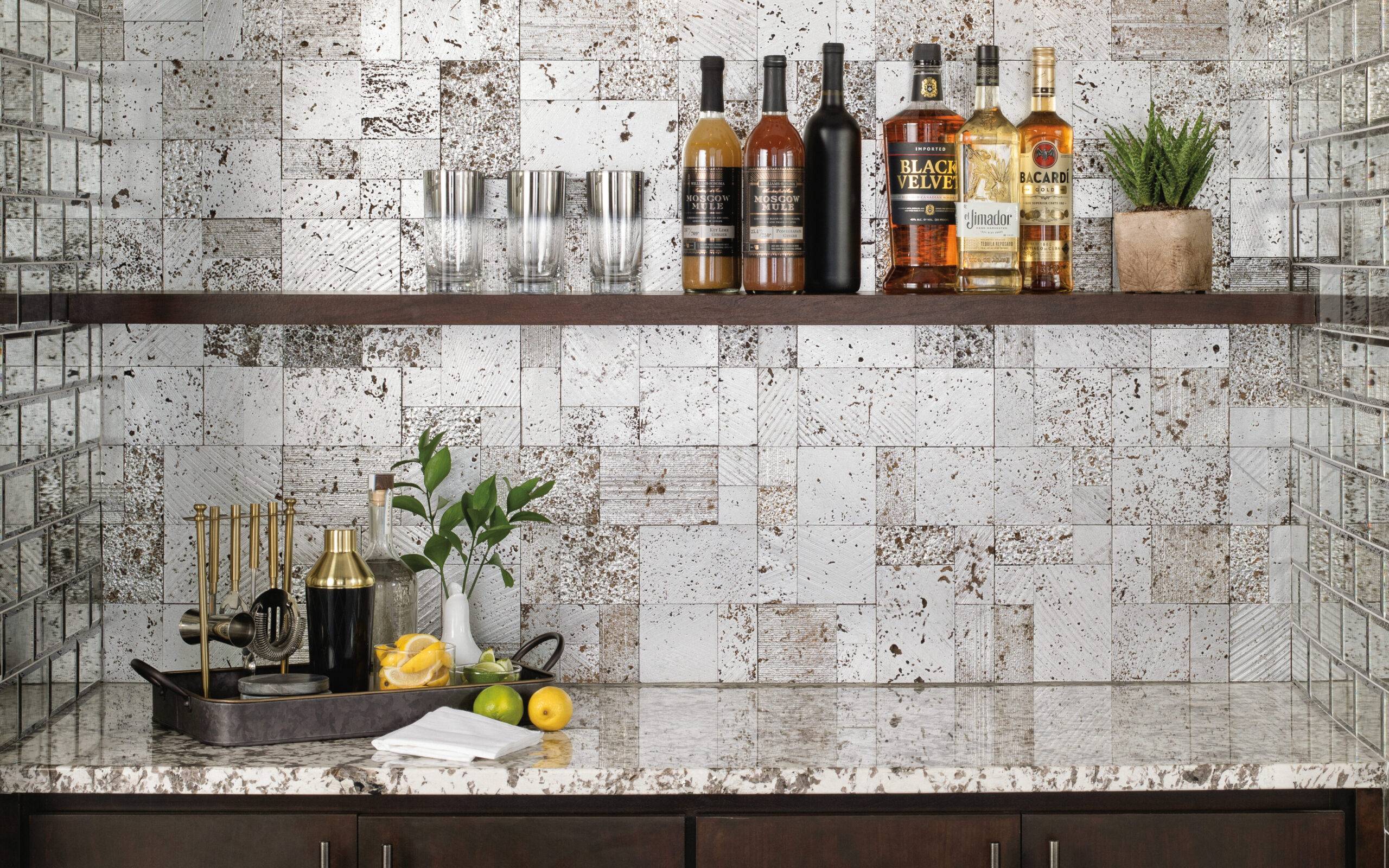A bar backsplash using 12" x 12" mosaic tiles  with a three -dimensional design, highlighted by a metallic silver finish offering a range of textures, incorporating modern lines, tumbled stone and softer touches.