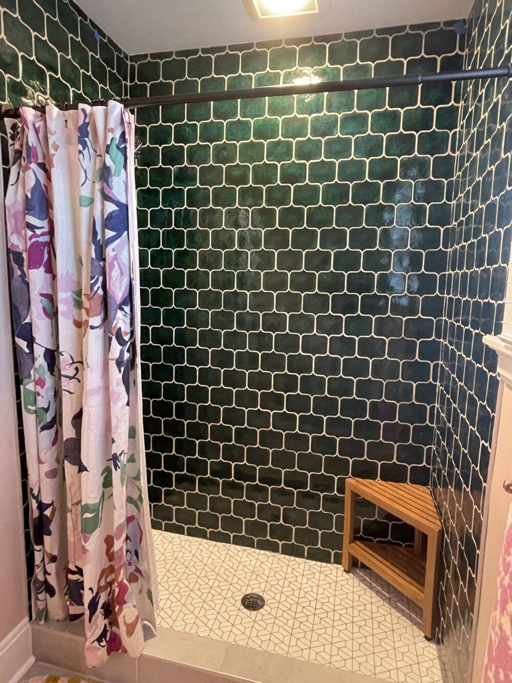 This shower features green text-bubble-shaped wall tile and white half-hexagon floor tile. 