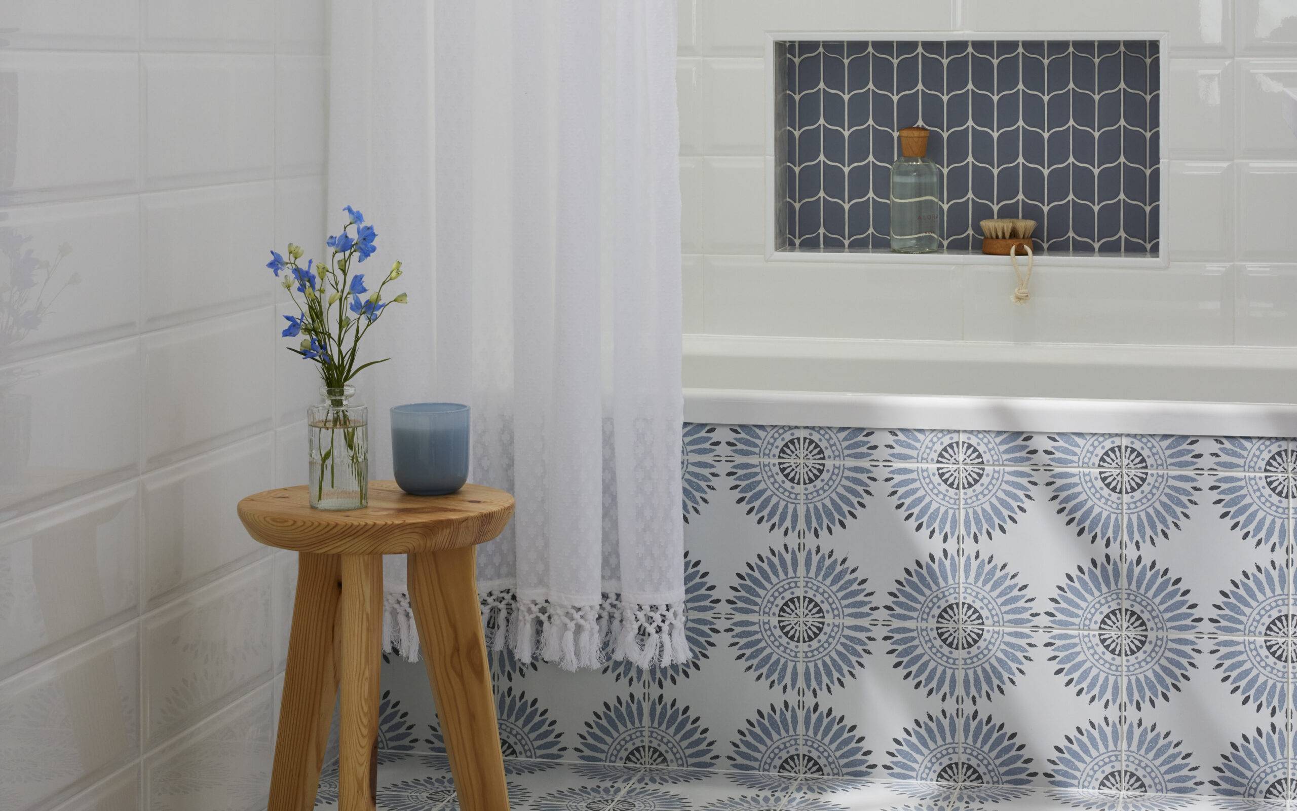 Bathroom featuring blue and white patterned tile on the floor and up the exterior side of the tub wall.