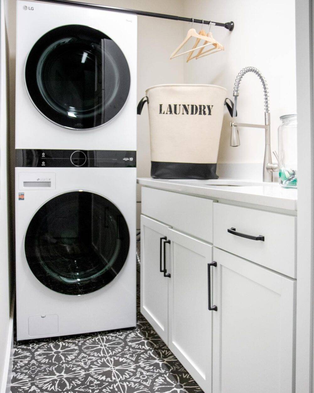 This clean and bright laundry room features a black and white patterned tile. 