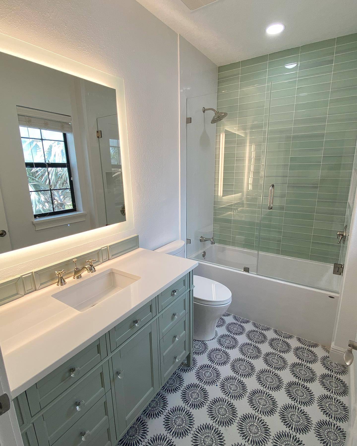 This bathroom feature mint green subway tile shower wall and a black-and-white floral pattern floor. 