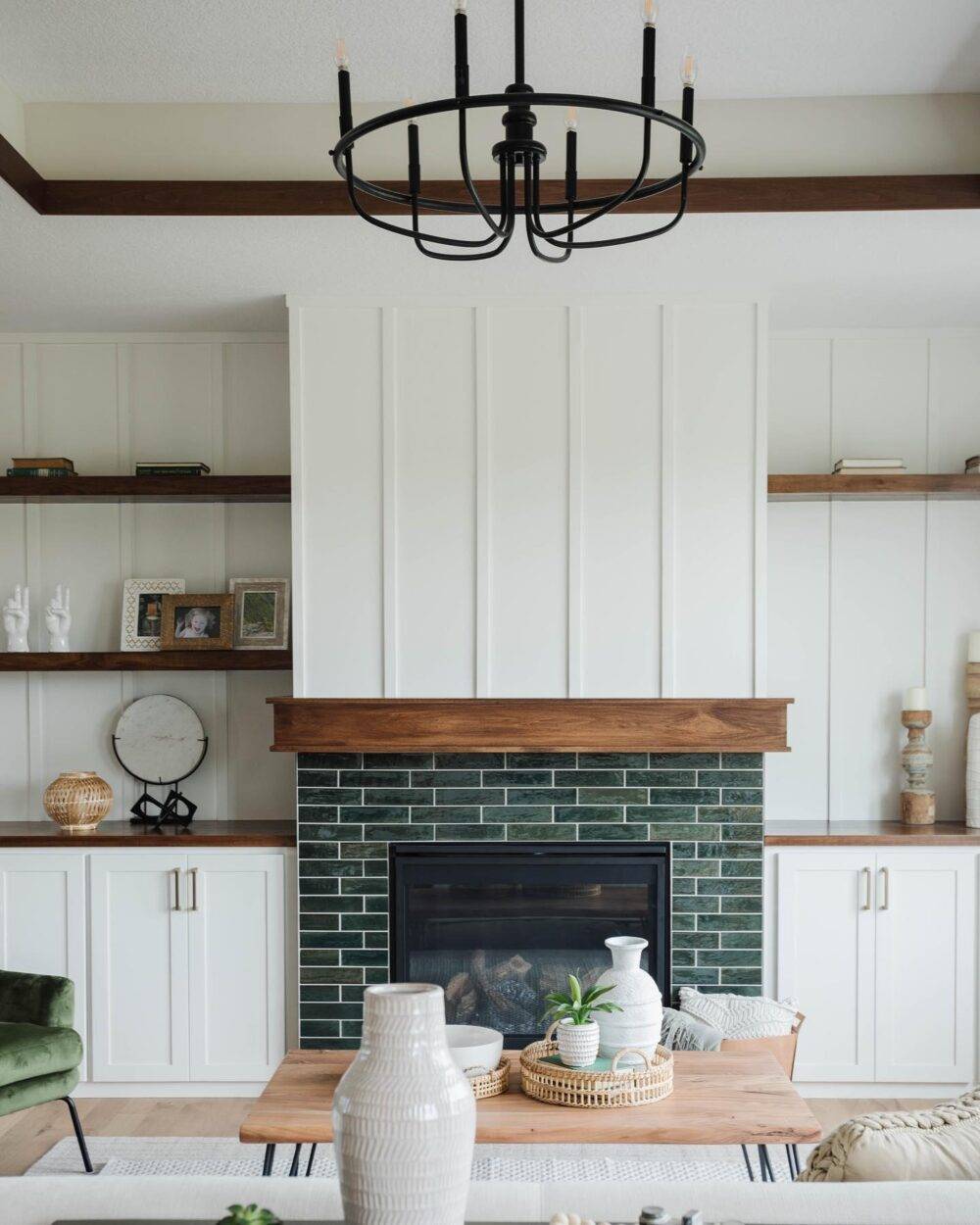 This bright and airy living room features white walls and a green handmade-look tiled fireplace. 