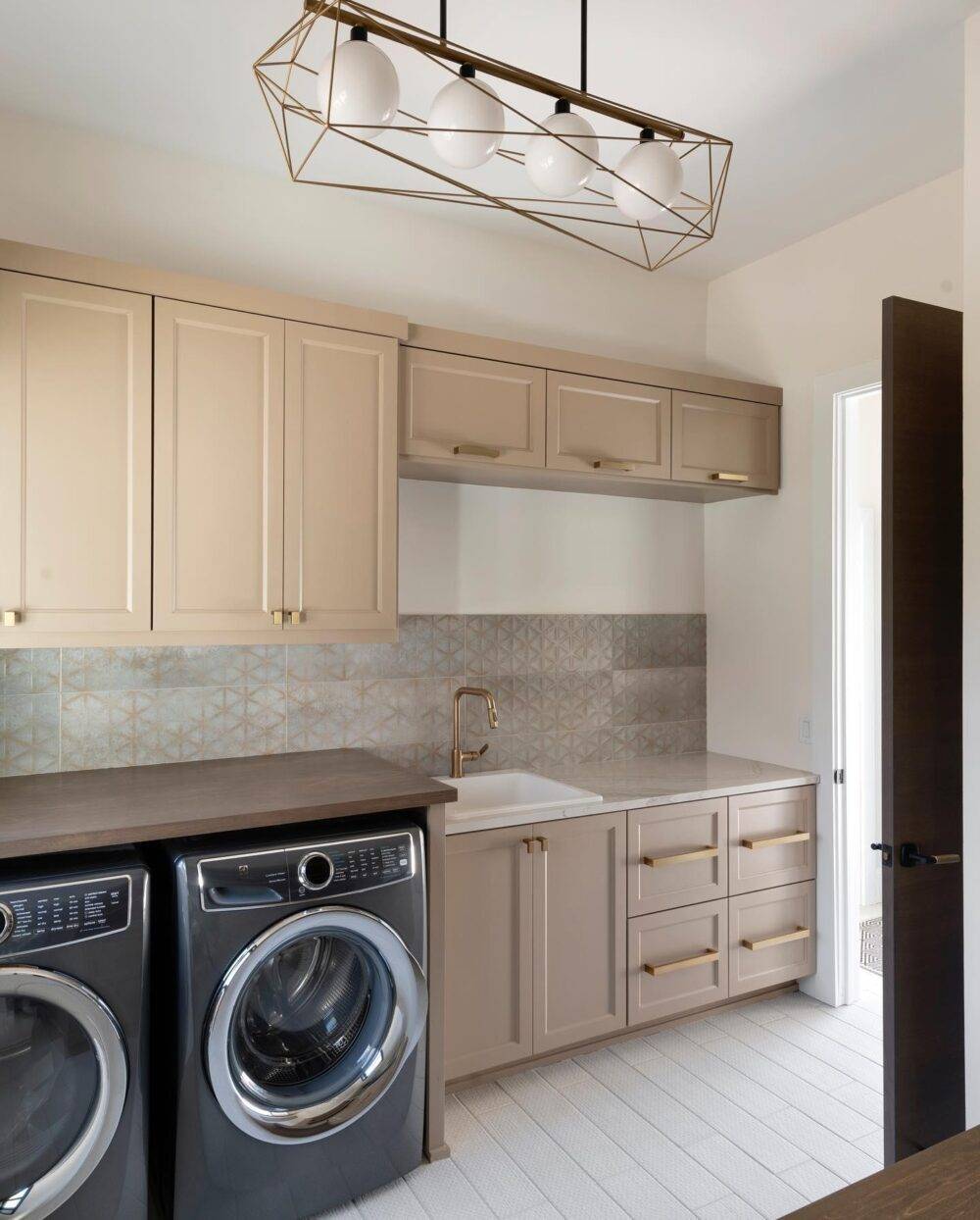 This neutral laundry room features a raised patterned beige wall tile. 