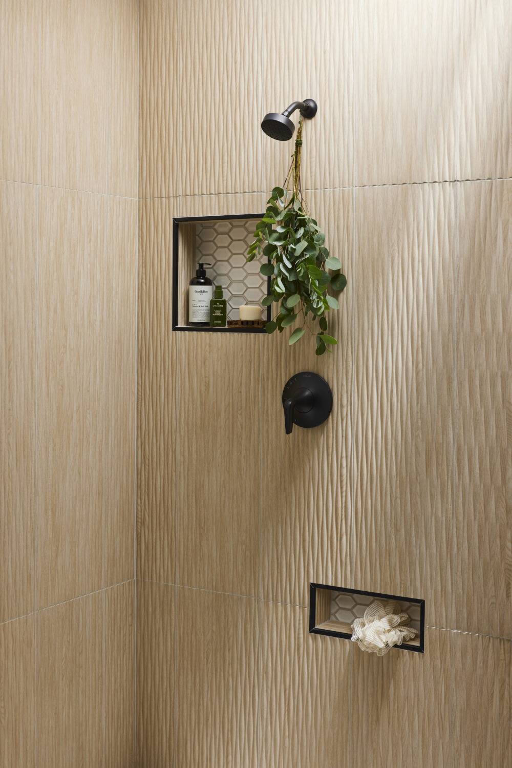 A shower with wood-look fluted tile and shower niches that feature elongated hex tile. 